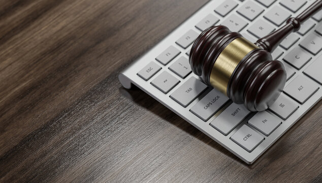 Gavel at the computer keyboard: Legal and law concept. Wooden hammer of justice and order