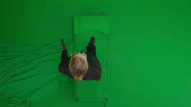 Portrait of female in suit on chroma key green screen. Blonde business woman in formal outfit walking with briefcase. Top view.