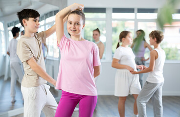 Girl dances Latin dance with male teenager partner during choreography lesson. Group training and...