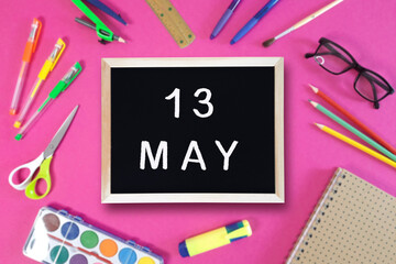 May 13 written in chalk on black board. Calendar date 13th of May on chalkboard on pink blurred...