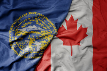 big waving realistic national colorful flag of nebraska state and national flag of canada .