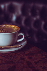 A cup of coffee standing on a vintage style table. Fresh cappucino with a sugar stick. Cozy cafe atmosphere. - 762757694