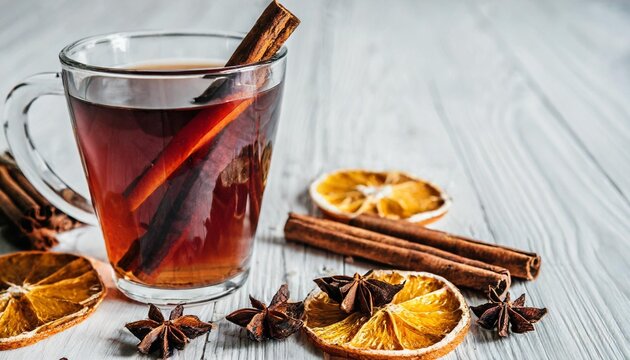 concept of warm drinks for cold weather comfort side view image of a cup of apple cider cinnamon sticks dried orange and anise on a white background