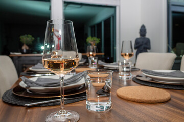 Table setting with wine glasses filled with rose under mood lighting.