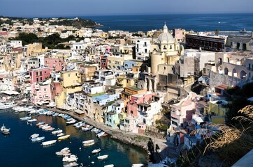 Panoramic view of beautiful Procida in sunny summer day. Colorful houses, fishing boats and yachts in Marina Corricella, Procida, Italy, Naples