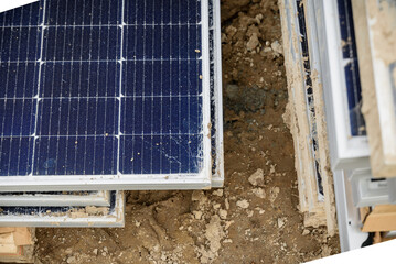 Damaged and cracked solar panels with fractured glass lie stacked on the sandy construction site. Concept of damage from inappropriate delivery standards.