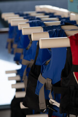 Multiple rows of neatly hung life vests on a rack, symbolizing orderliness and water safety measures