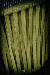 An up-close examination of the weave and texture of a green chair, highlighting intricate...