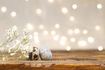 Easter card with quail eggs on wooden table and blurred lights. Beautiful shiny background with...