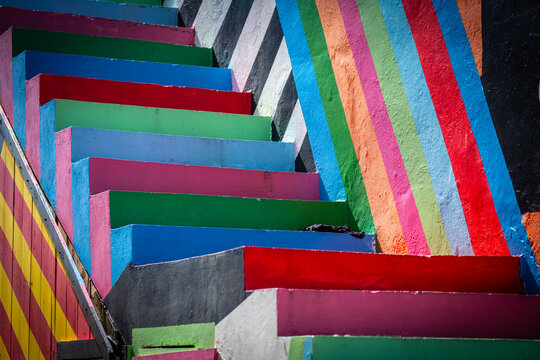 A high-angle perspective of an outdoor staircase with stripes in multiple colors creating a striking visual