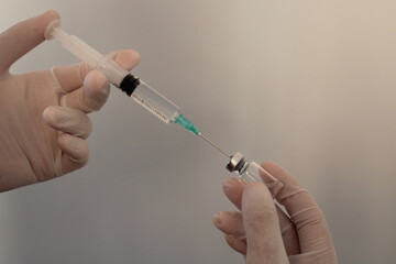 A hand holding a syringe with a syringe in it. Syringe in hand of doctor and nurse. Vaccine bottle.