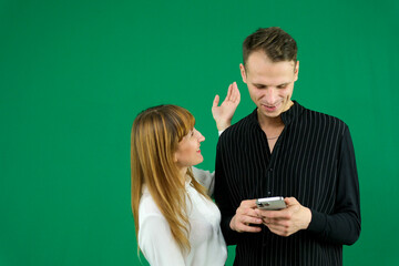 man and woman with gadgets tablet phone in hands on green background talking laugh holding meeting learning to work on Internet flirting relationships flirting couple solving issue positive emotions