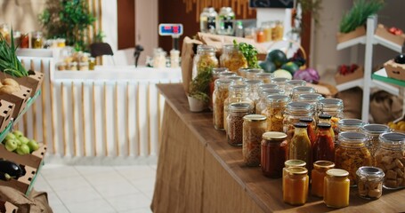 Additives free pantry staples on eco friendly zero waste supermarket shelves. Organic food in biodegradable reusable glass jars on display in empty local neighborhood grocery store
