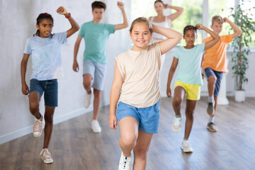 Obraz premium Positive cheerful children studying modern style dance in class indoors
