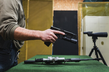 A pistol with a weapon flashlight in a man's hand at a shooting range.