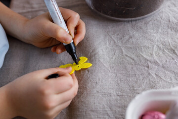 Child making handmade yellow rabbit decoration and drawing with black marker - obrazy, fototapety, plakaty