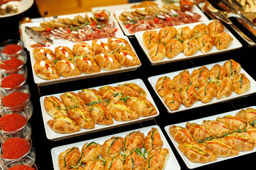 A lavish spread of gourmet appetizers, featuring golden croissants garnished with fresh herbs and a...