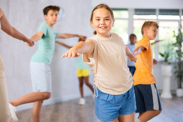 Positive preteen children learning to dance waltz in pairs in choreography class