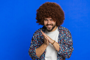 Sneaky cunning young man with Afro hairstyle wig with tricky face gesticulating and scheming evil...