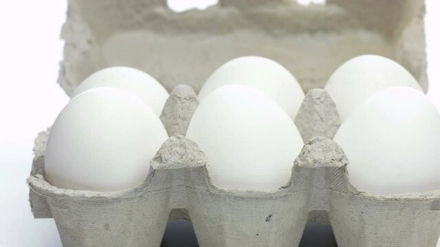 White whole eggs in egg carton box slowly rotating	
