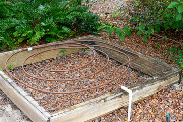 A wooden flower box with small copper coiled in circles fixed to a water system. The micro...