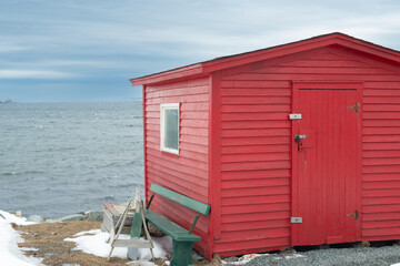 A bright red wooden building overlooking the Atlantic Ocean. The accessory building has a wooden...