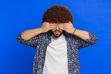 Don't want to look at this, awful. Afraid shocked man with Afro hairstyle wig closing eyes with...