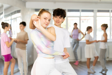 Teenage boy and girl dancing ballroom waltz dance in studio
