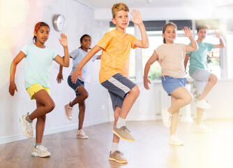 Man child performs movements during warm-up, limbering-up part of workout together with peers. Group of young girls and guys dance modern hip hop in fitness club unfocused