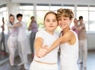 Group of positive teenagers learning to dance tango in a dance studio