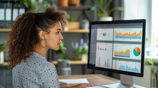 A black female data analyst working on the computer in a bright modern office