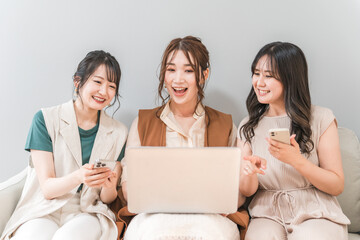 家で一緒にスマホとノートパソコンを使う女性・友達・ママ友・仲間
