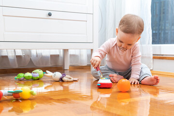 Baby interacts with toys with interest while playing in the room