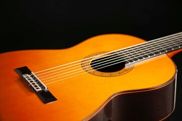 Obraz premium Classical Spanish flamenco guitar close up, dramatically lit isolated on black background with copy space.
