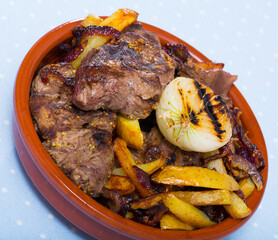 Image of braised tasty beef with potatoes and onions at clay pot on table