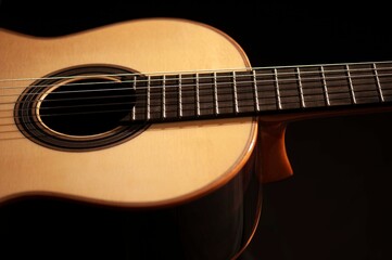 Obraz premium Classical Spanish flamenco guitar close up, dramatically lit isolated on black background with copy space.