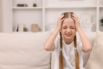 Little girl suffering from headache at home. Space for text