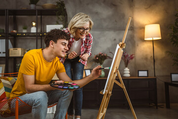 Fototapeta na wymiar mother and son paint at home mentor artist help teach to create art