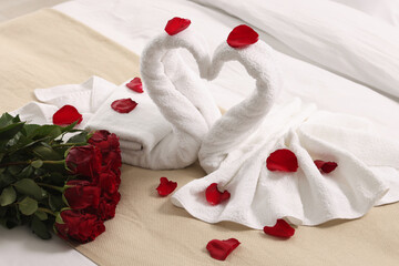 Honeymoon. Swans made of towels and beautiful red roses on bed