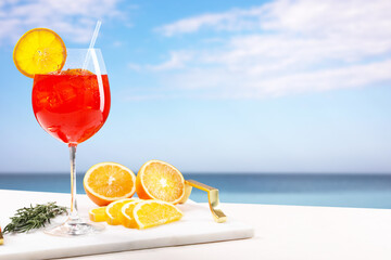 Aperol spritz cocktail in glass, orange slices and rosemary on table at beach. Space for text