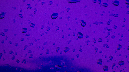 Water drops on a purple background. Texture of water drops on the glass.