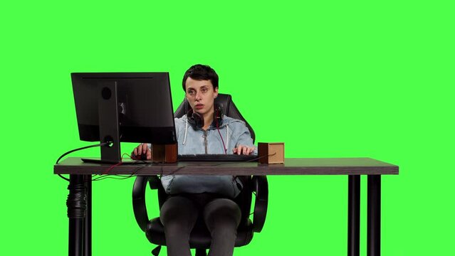 Young woman playing video games online on pc at desk against greenscreen backdrop, winning global e sport championship on computer. Player feeling joyful and content with her victory. Camera B.