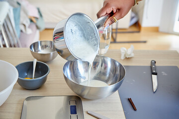 Obraz na płótnie Canvas Black Hand Pouring Cream Mixture into a Bowl