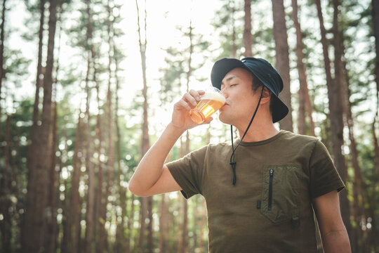 キャンプ場でビールを飲む男性キャンパー（お酒・アルコール・クラフトビール・発泡酒）
