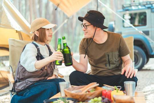 キャンプ場でお酒を飲む夫婦・カップルキャンパー（ビール・キャンプ飯・ご飯）
