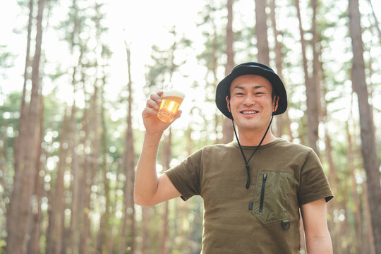 キャンプ場でビールを飲む男性キャンパー（お酒・アルコール・クラフトビール・発泡酒）
