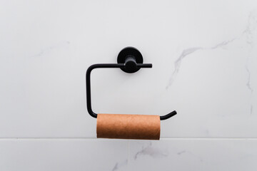 empty toilet paper roll on black roll holder on white marble tiled wall, humour image about running...
