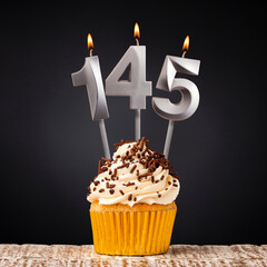 birthday cupcake with number 145 candle - Celebration on dark background