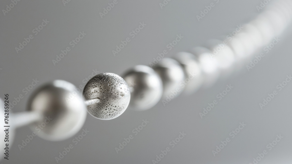 Poster a detailed view of a series of small silver beads arranged in a line along a thin wire. each bead ha