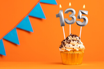 Birthday cupcake with candle number 135 - Orange background